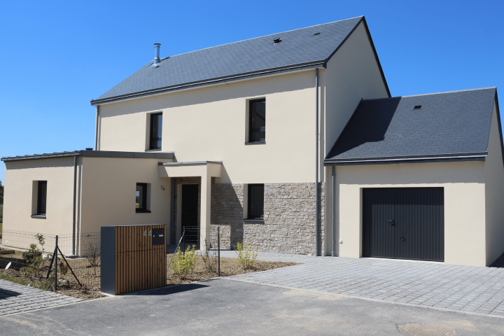 Maison contemporaine à étage avec garage intégré, toiture double pente, façade claire et parement pierre